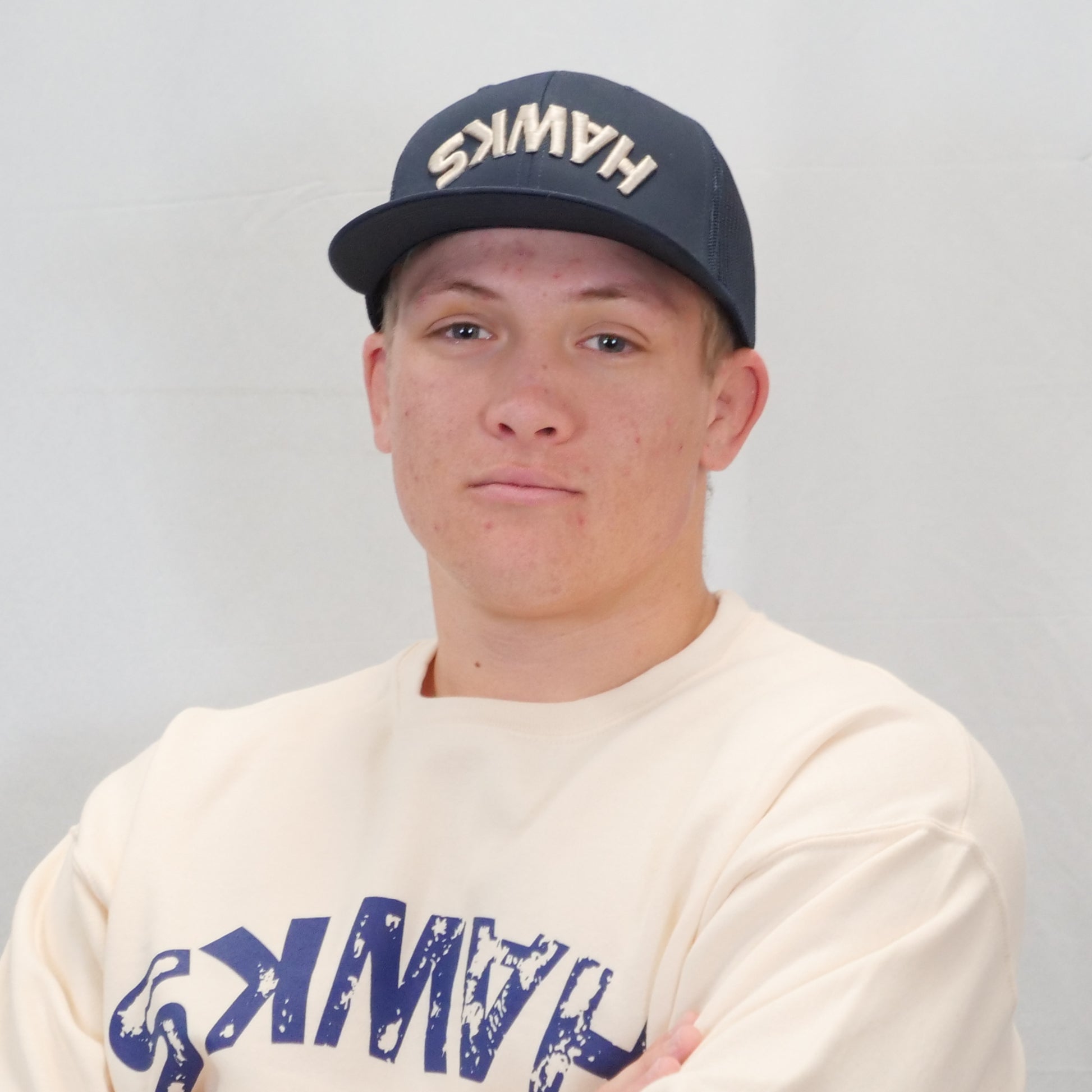 Person wearing a cap and t-shirt with 'HAWKS' branding on a plain background