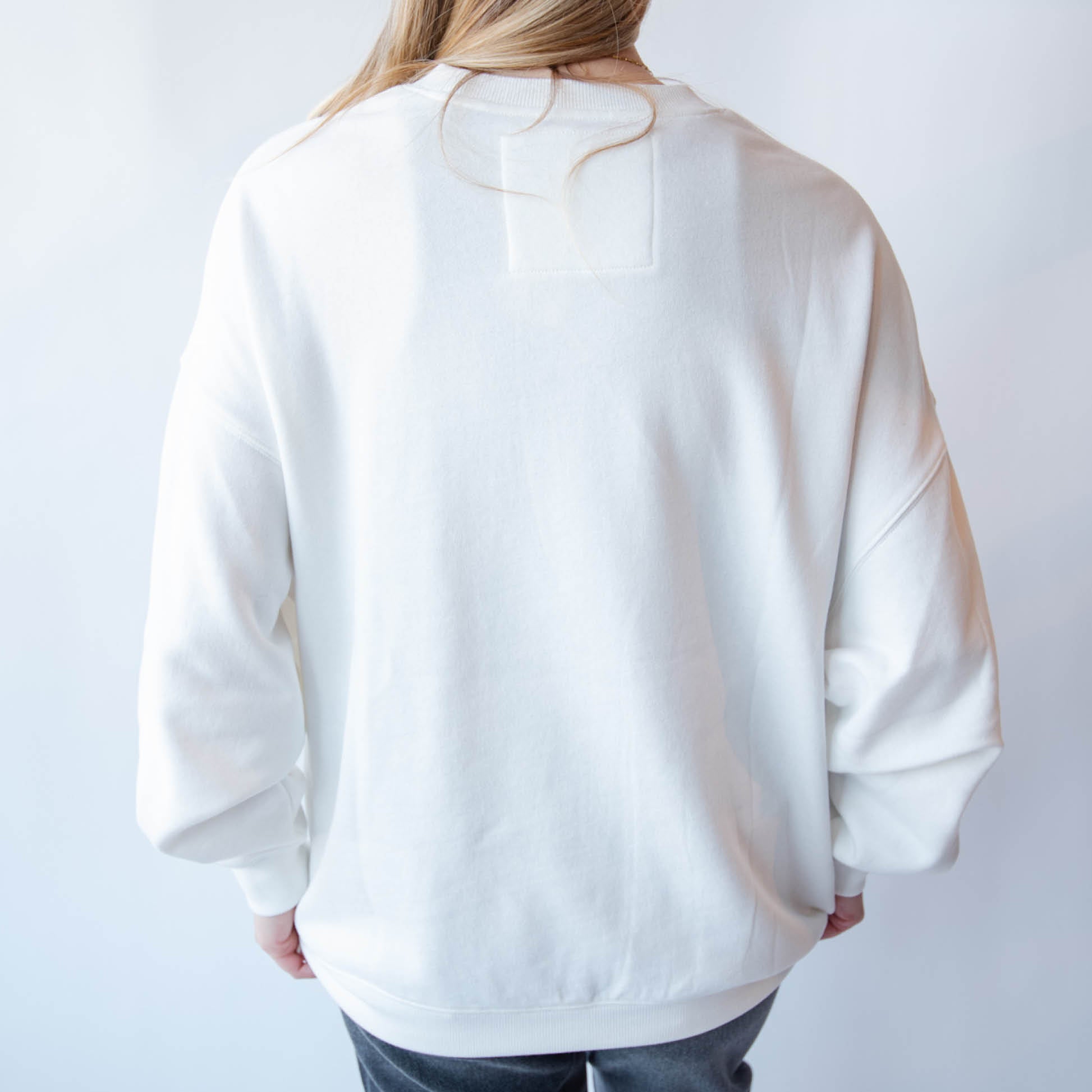 Person wearing a white oversized sweatshirt against a plain background