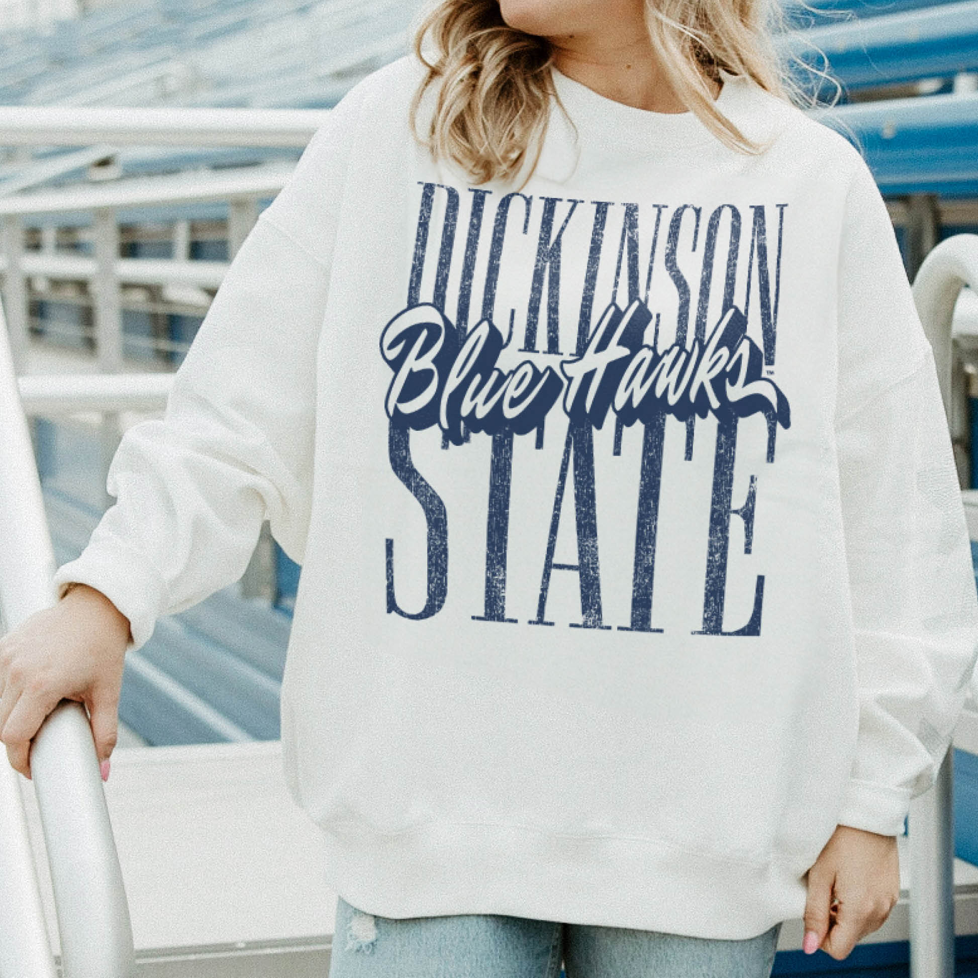 Person wearing a white sweatshirt with 'Dickinson Blue Hawks State' text, standing in an outdoor setting.