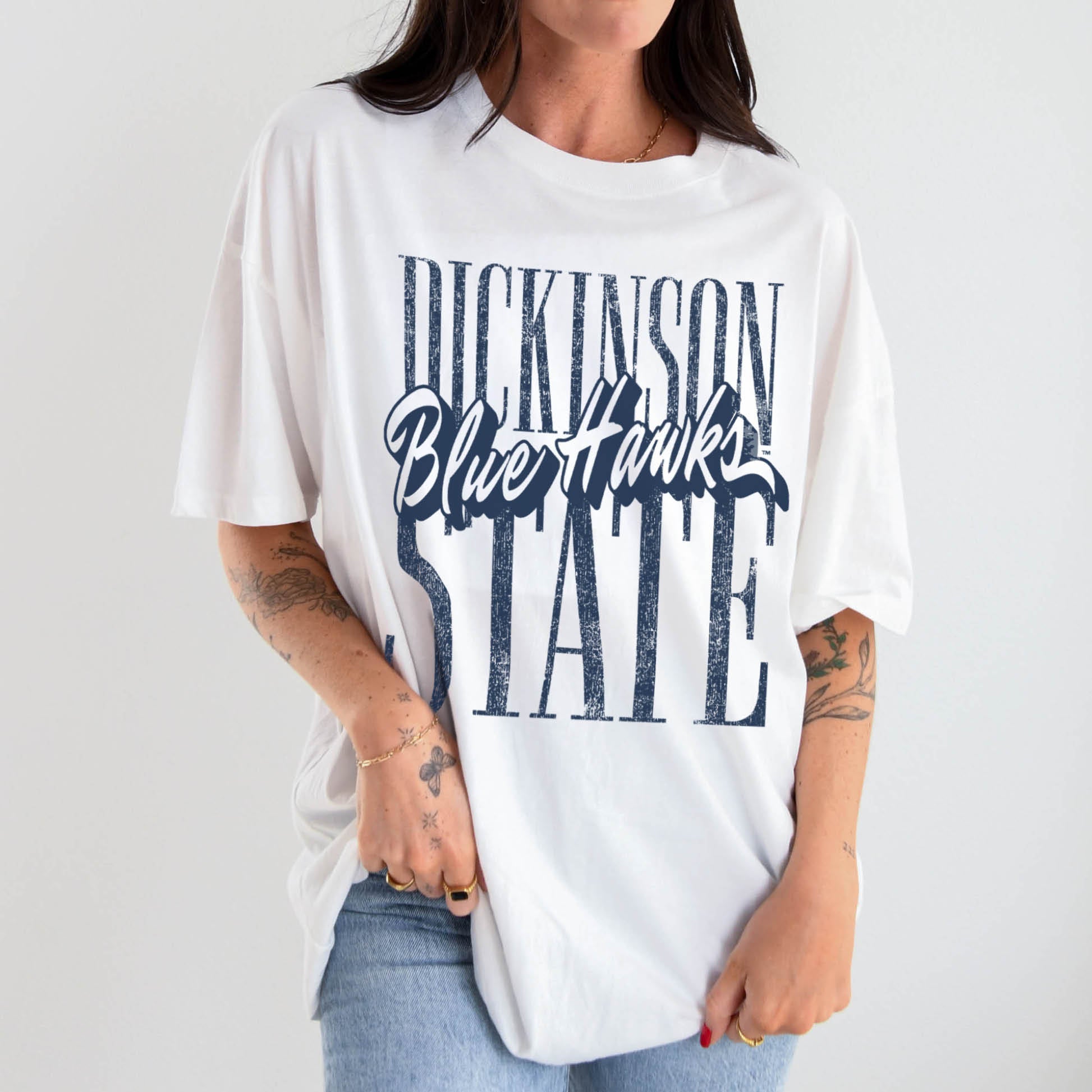 Person wearing a white t-shirt with text "Dickinson State Blue Hawks" on a plain background