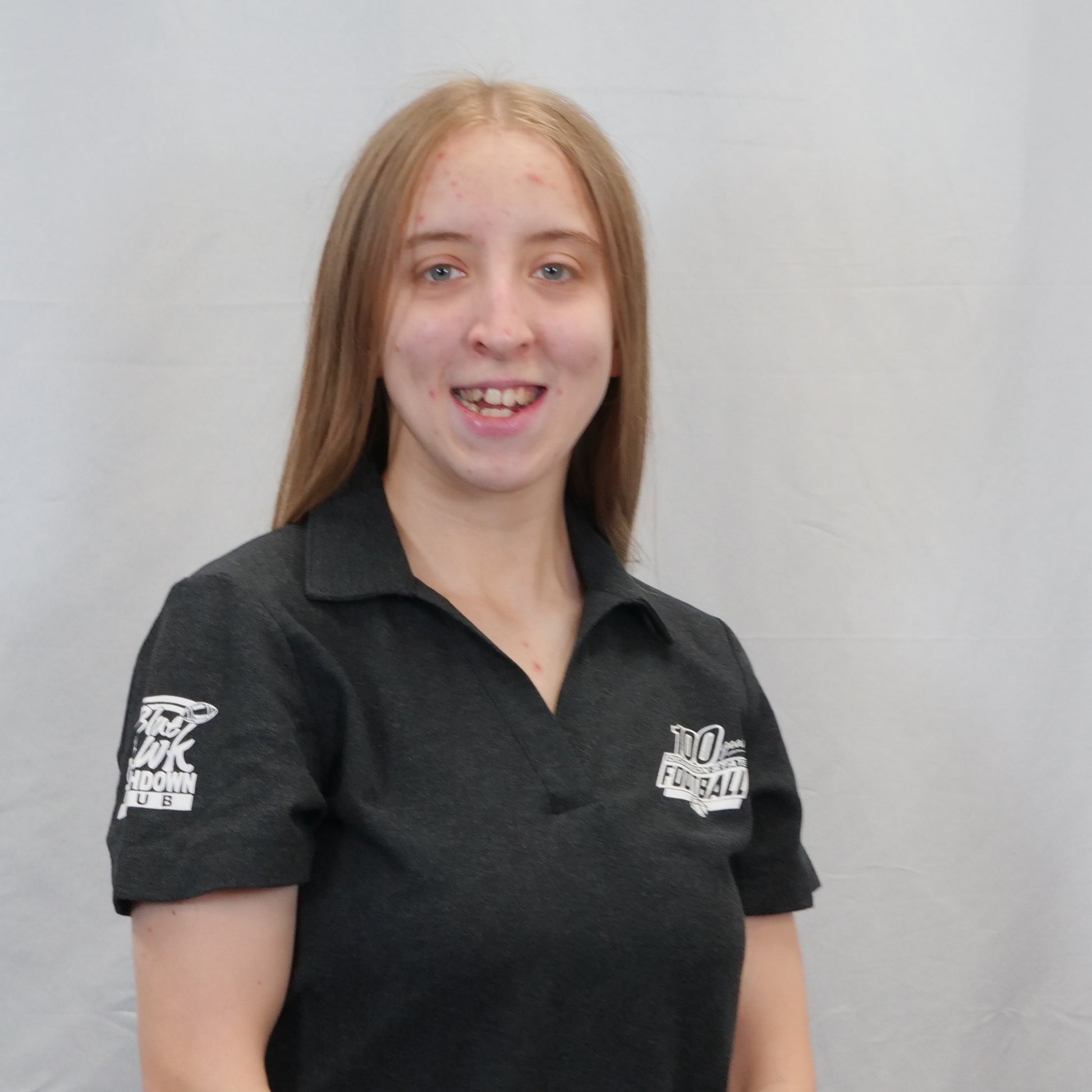 Person wearing a black polo shirt with logos on a gray background