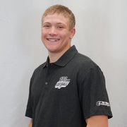 Person wearing a black polo shirt with logos on a plain background