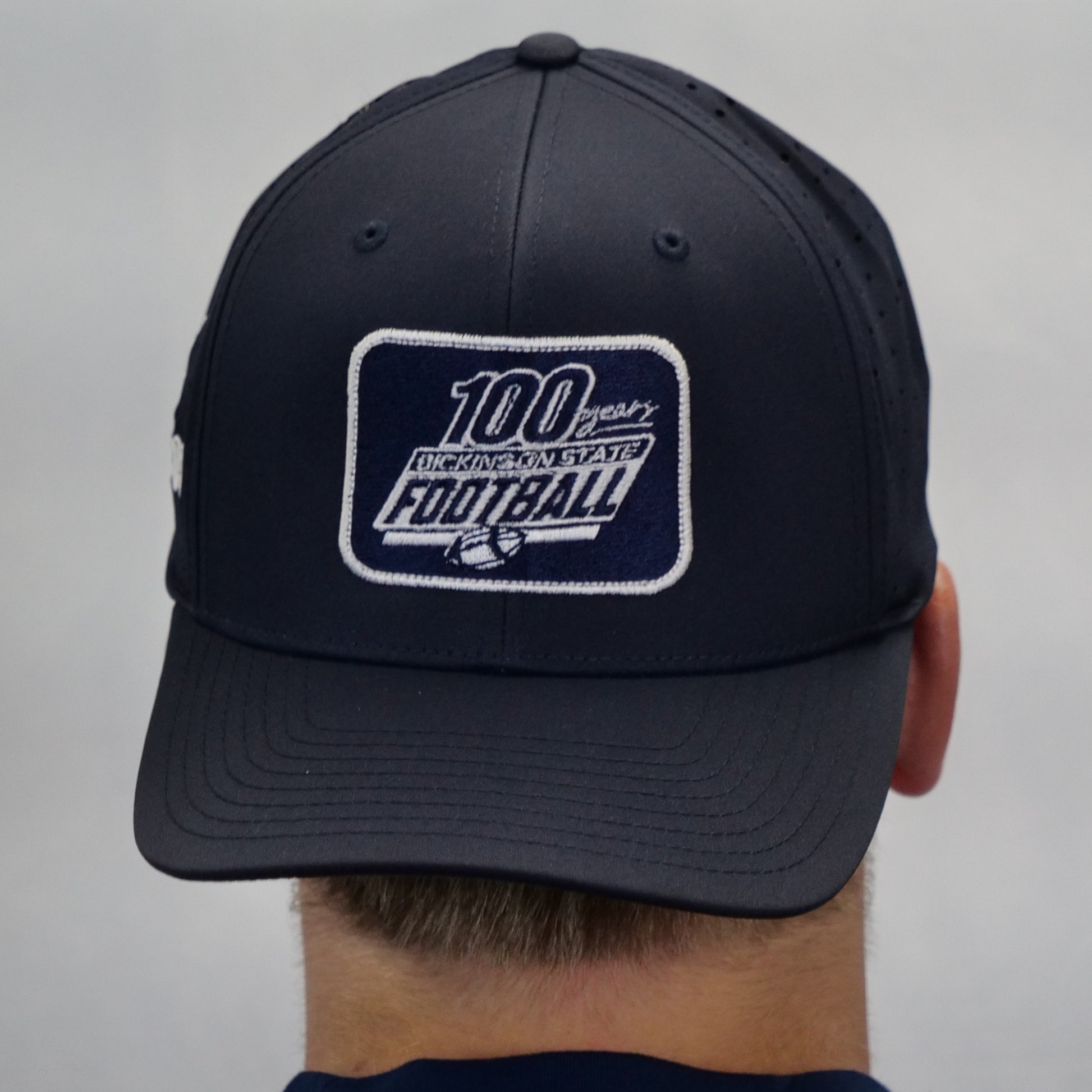 Black cap with a '100 years of Washington State Football' patch on a gray background